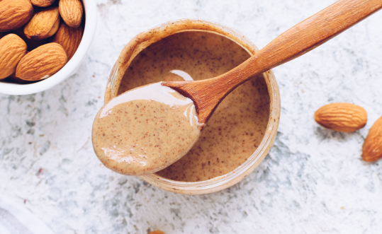 A bowl with spoon of almond butter in Snack Baby's Apple Carob Crunch Vegan dog treats